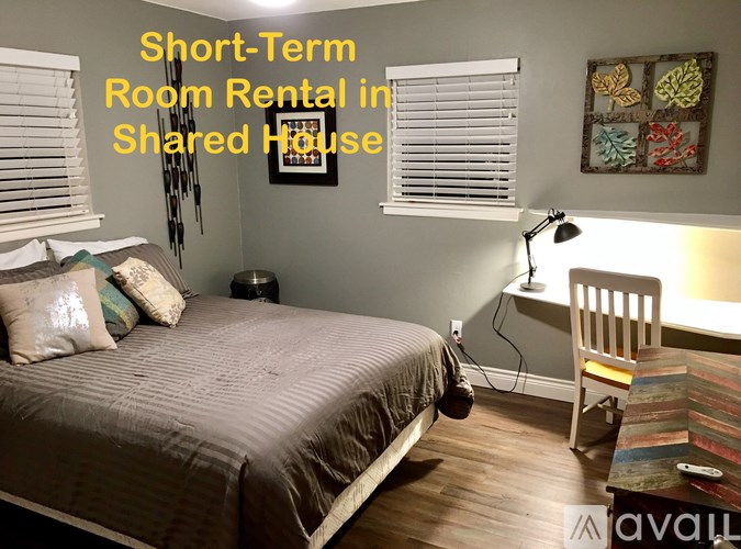 A bedroom with a bed, desk, and chair is available for short-term room rental in a shared house.
