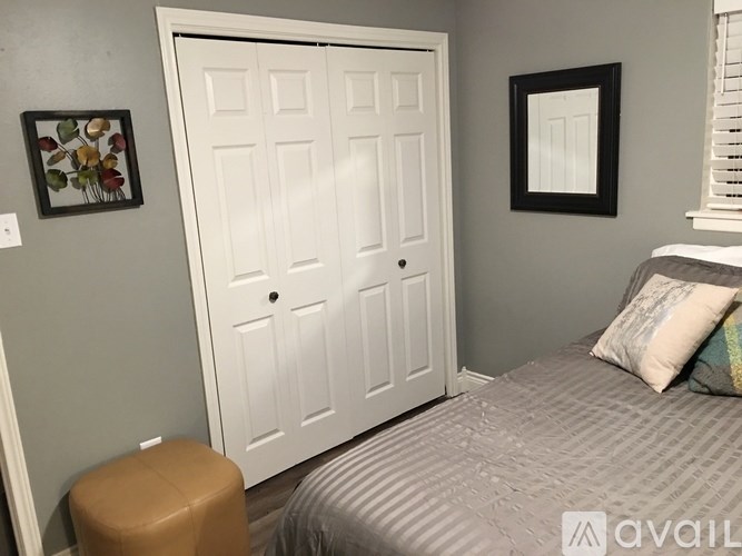 A bedroom with a bed, a door, and a picture on the wall.
