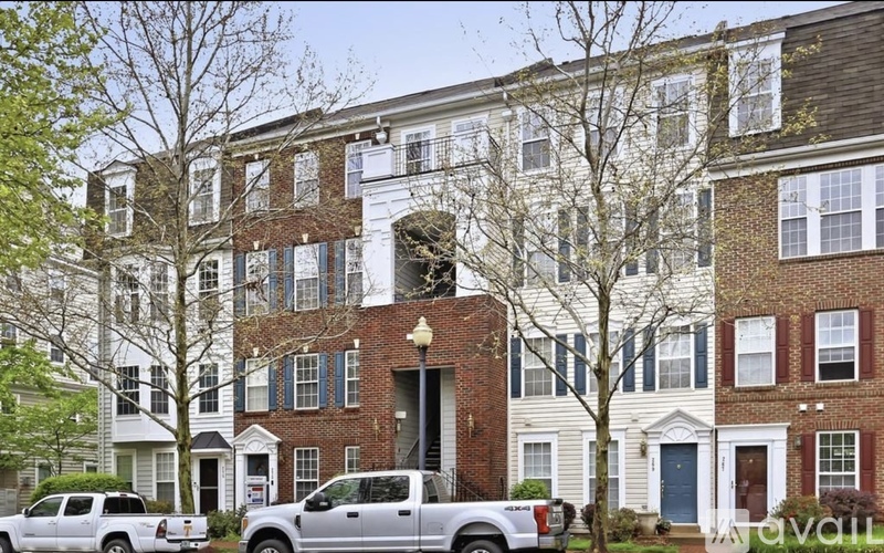 A row of townhouses with cars parked in front.