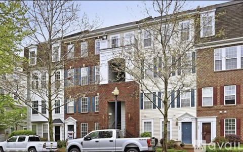A row of townhouses with cars parked in front.