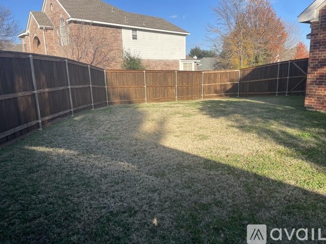 A backyard with a wooden fence and a house in the background.