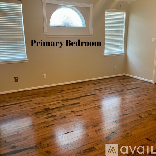 A room with wooden flooring and a window with blinds.