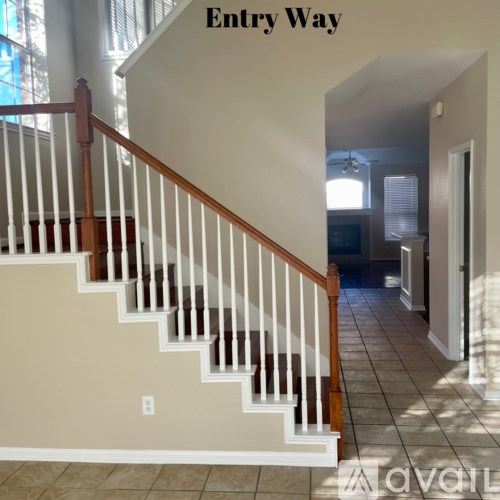 A staircase with a wooden handrail and white balusters leading to a foyer.