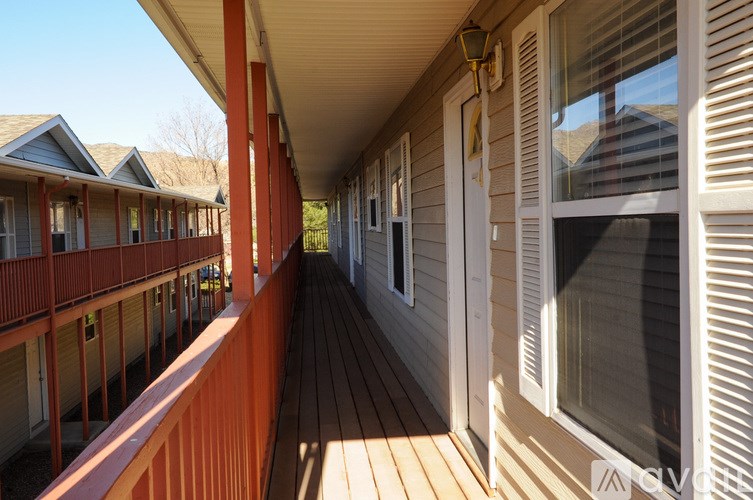 A long wooden porch with a red railing.