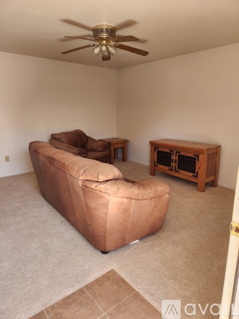 A living room with a brown sofa and a wooden table.