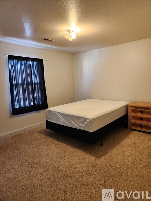 A bedroom with a bed, dresser, and carpet.