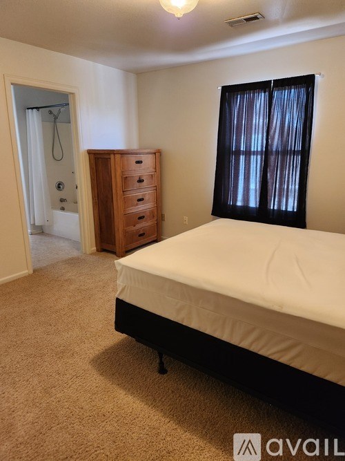A bedroom with a bed, dresser, and window.