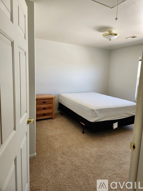 A bedroom with a bed, dresser, and carpeted floor.