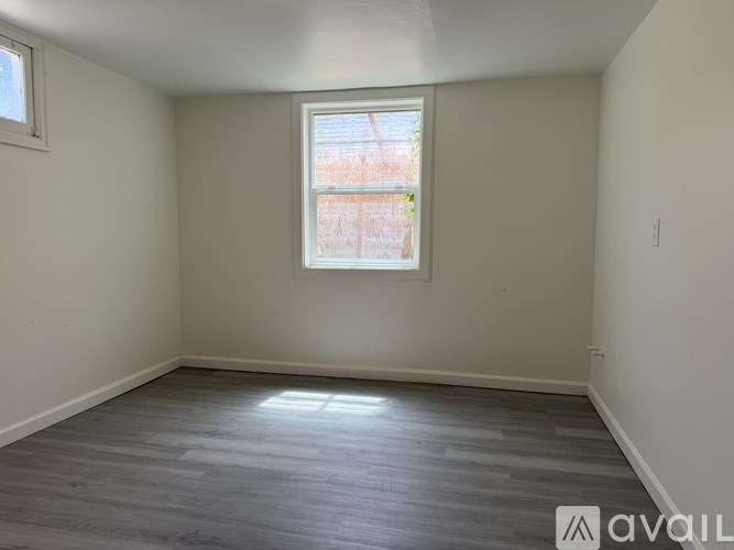 A room with a window and wooden flooring.