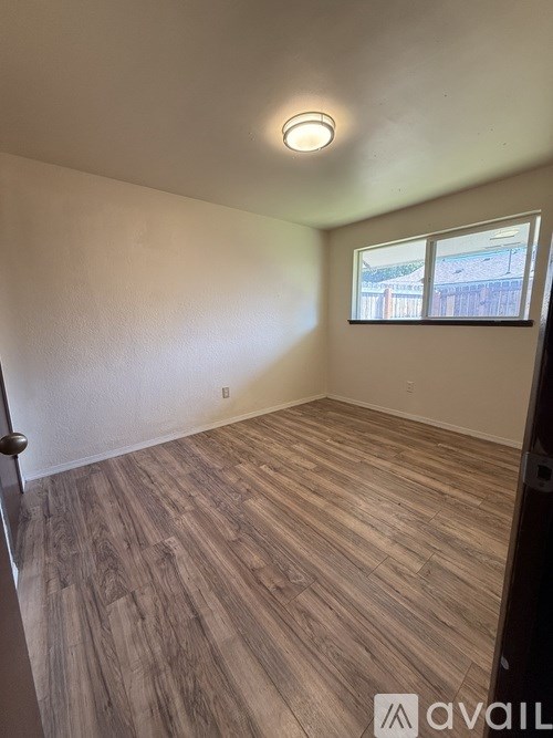 A room with wooden flooring and a window showing an outdoor view.
