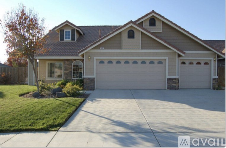 A house with a garage and a tree in front of it.