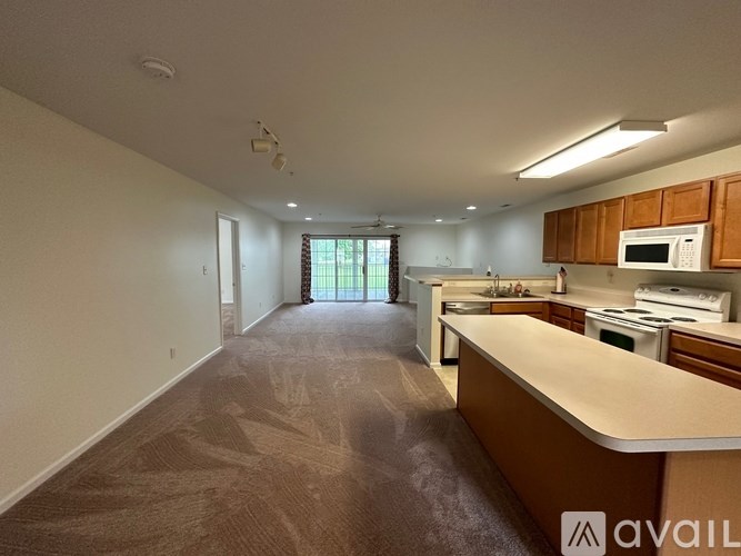 A spacious kitchen with brown carpeting and wooden cabinets.