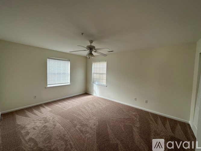 A room with a carpeted floor and a ceiling fan.
