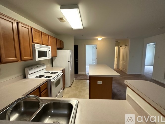 A kitchen with a stove top oven, microwave, refrigerator, and sink.
