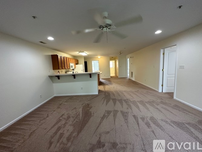 A room with a carpeted floor and a ceiling fan.