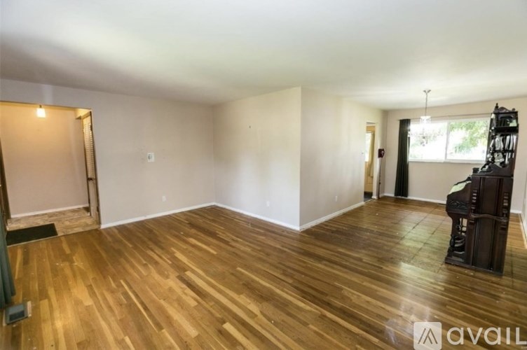 A room with wooden flooring and a piano in the corner.