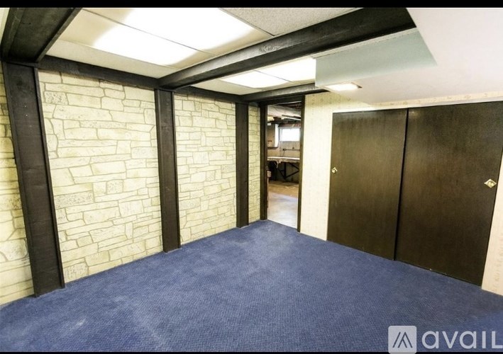 A room with a blue carpet and a brick wall.