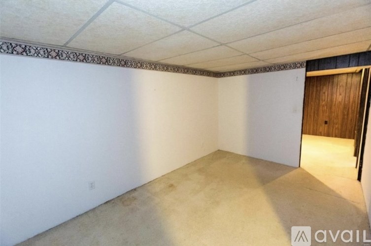 A room with a carpeted floor and a wooden door.