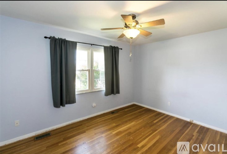 A room with a ceiling fan and a window with curtains.