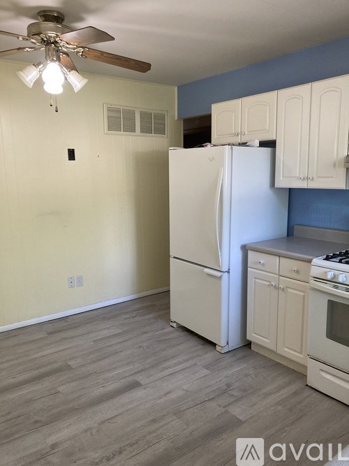 A kitchen with a white refrigerator and a ceiling fan.