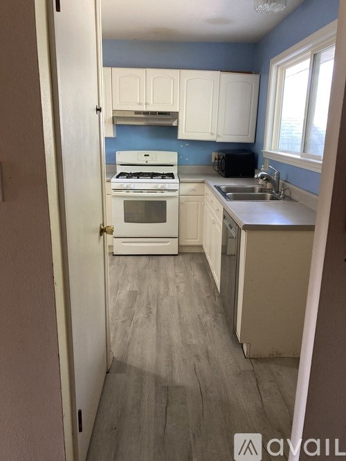 A kitchen with white cabinets and a blue backsplash.