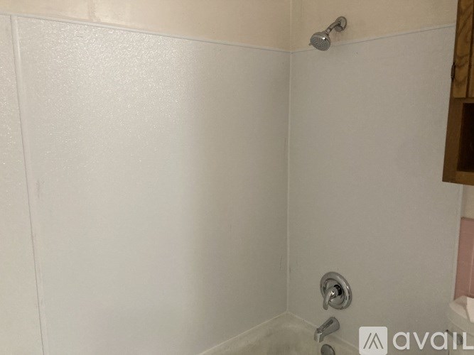 A white tiled shower stall with a silver shower head and faucet.