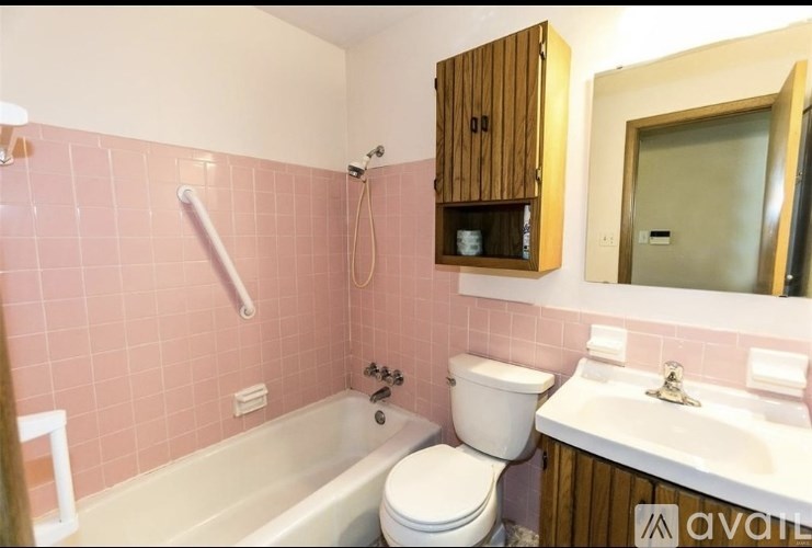 A bathroom with pink tiles and a white bathtub.