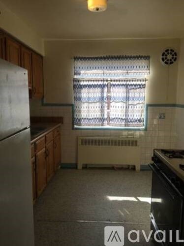 A kitchen with a refrigerator, stove, and a window with blinds.