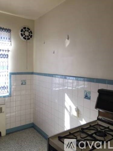 A kitchen with a gas stove and a window with a fan.