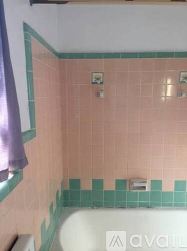 A bathroom with pink tiles and a white tub.