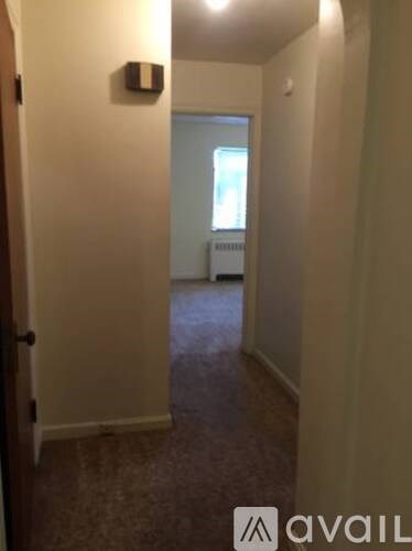 A hallway with a door on the left and a window on the right.