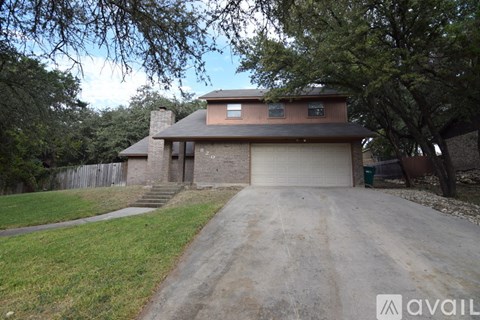 A house with a driveway and a tree in front.