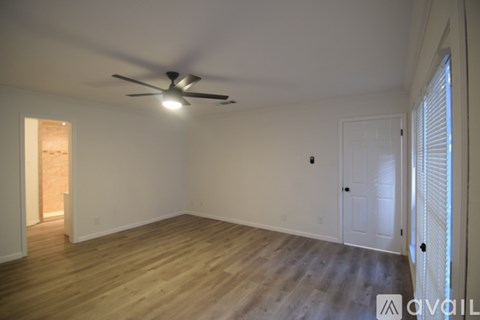 A room with a ceiling fan and wooden flooring.