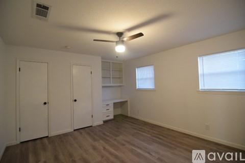 A room with a ceiling fan and a window with blinds.