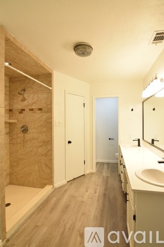 A bathroom with a sink, mirror, and shower.