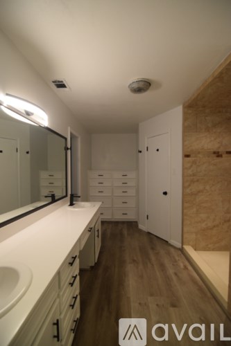 A bathroom with a sink, mirror, and wooden floors.