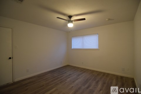 A room with a ceiling fan and a window with blinds.