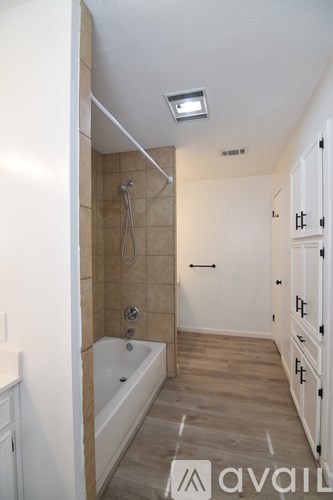 A bathroom with a tub, sink, and mirror.