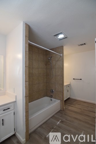 A bathroom with a tub, sink, and mirror.