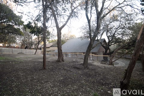 A tree-filled yard with a house in the background.