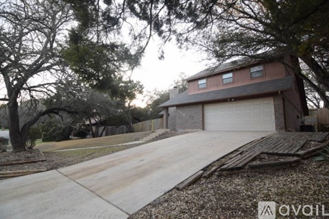 A house with a driveway and garage is surrounded by trees.