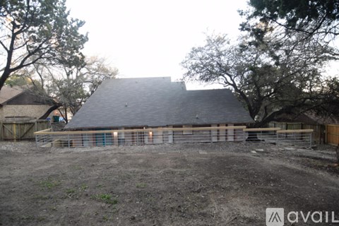 A barn with a metal roof and a fence in front of it.