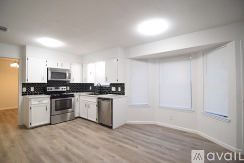 A kitchen with white appliances and a wooden floor.