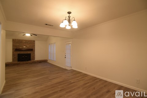 A large empty room with wooden floors and a fireplace.