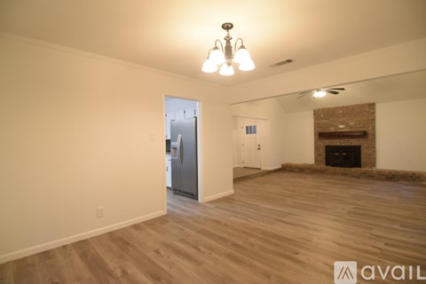 A spacious living room with wood flooring and a fireplace.