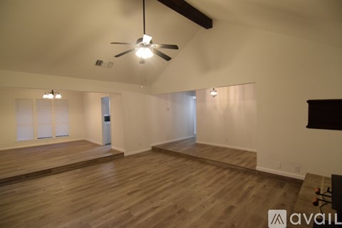 A spacious room with wooden floors and a ceiling fan.