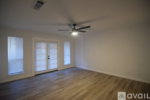 A room with a ceiling fan and wooden flooring.