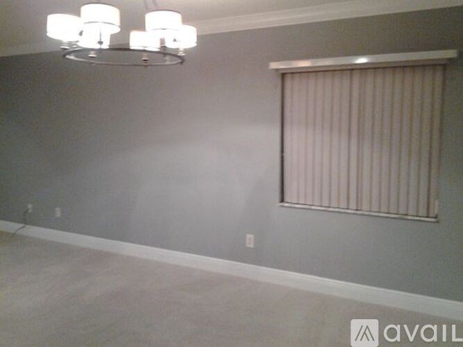 A room with a chandelier and a window with blinds.