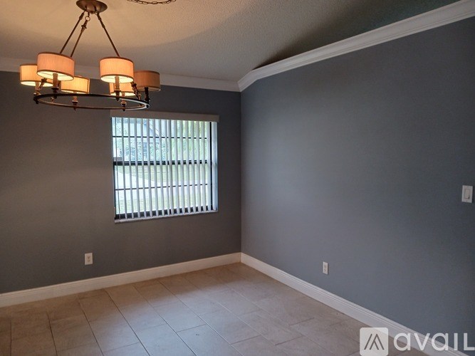 A room with a grey wall and a window with blinds.