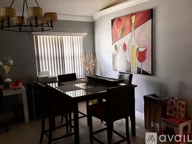 A dining room with a table and chairs and a painting on the wall.